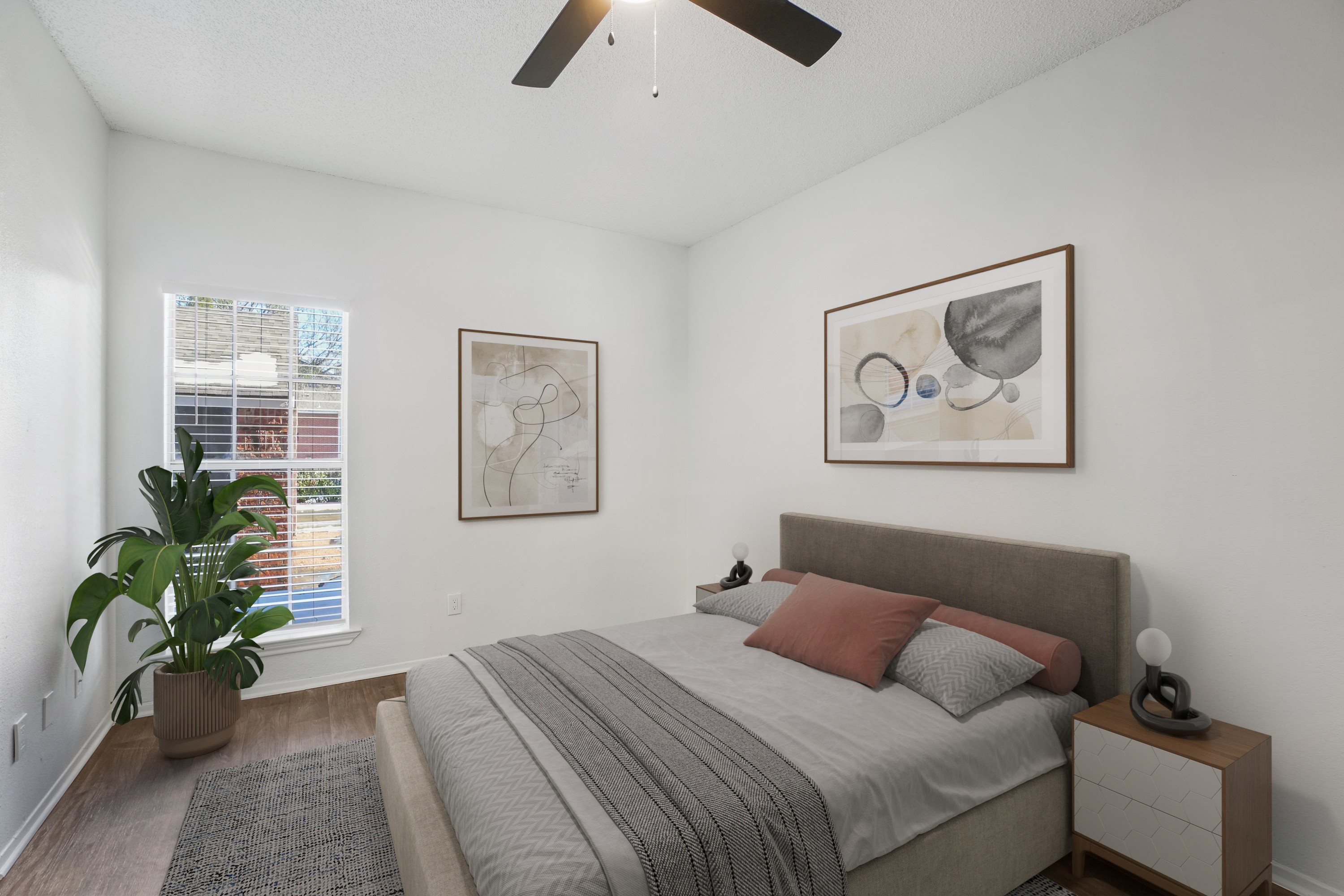 A bedroom with a bed, nightstand, and two framed pictures on the wall.